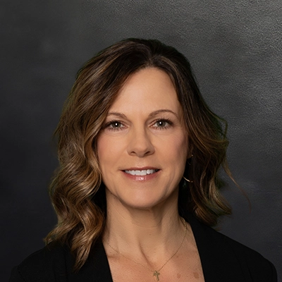 Chiropractor Amy Zimmerman Smiling In Front Of Black Wall